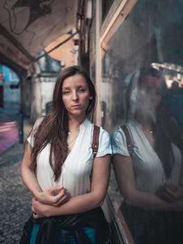 Fashionable woman poses in a city alleyway, reflecting urban style and mood.