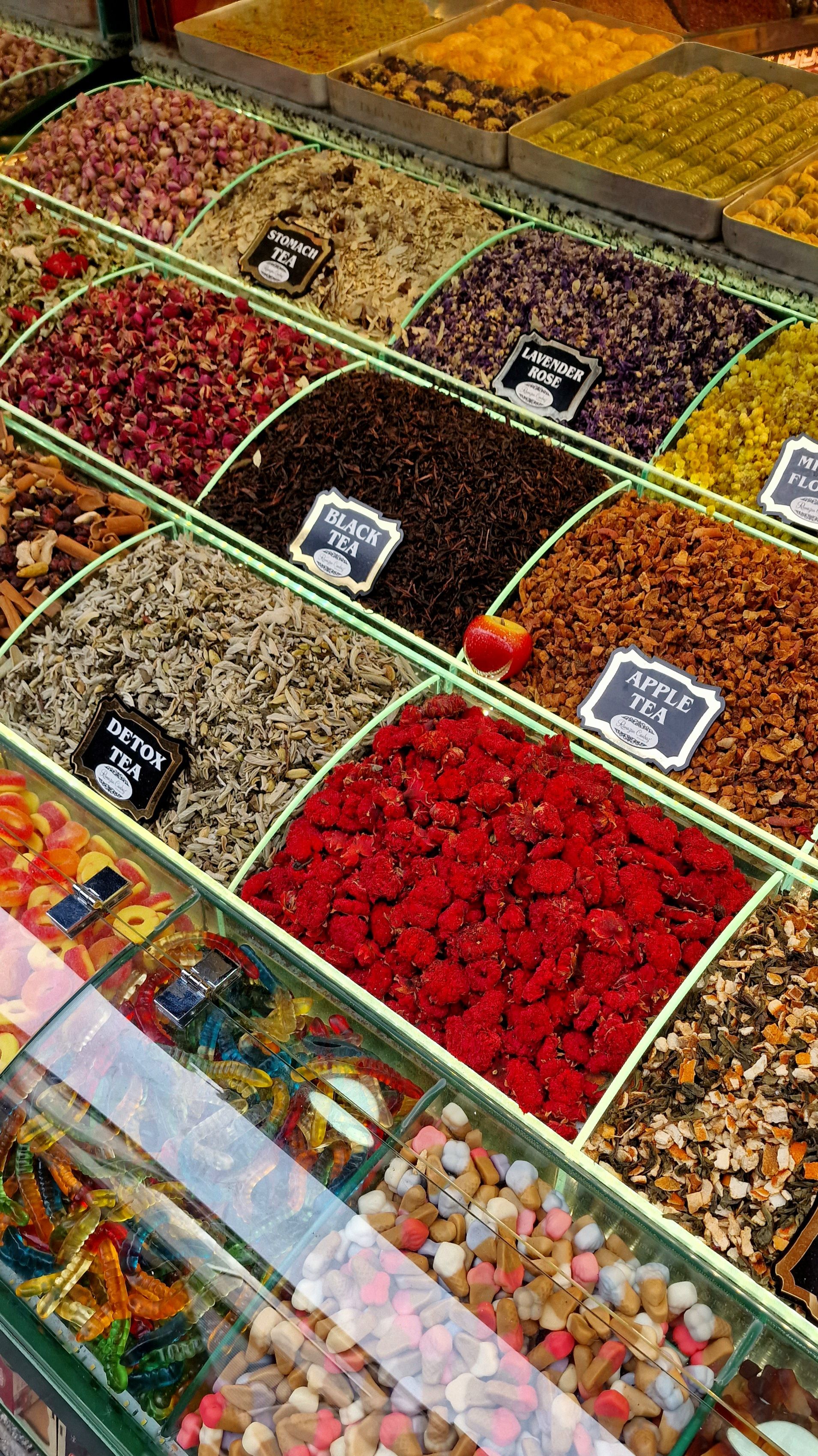 Colorful assortment of loose leaf teas and candies in a spice market display. - buying dry fruits online Pakistan