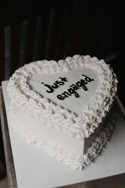 Elegant heart-shaped cake with floral frosting and 'Just Engaged' text, perfect for celebrations.