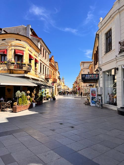 Free Sunlit quaint European street lined with historic buildings and cafes, showcasing architectural beauty. Stock Photo
