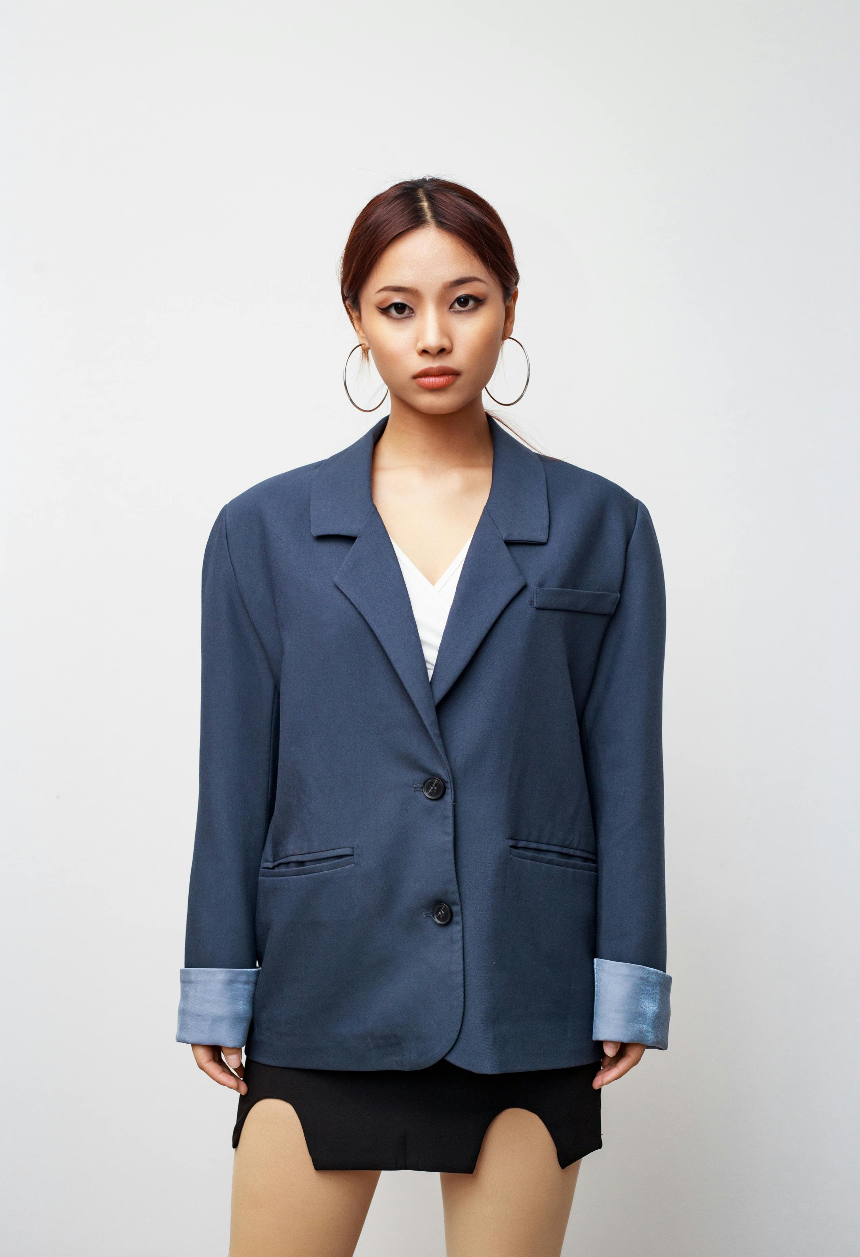 Free A fashionable young woman confidently poses in a formal blue jacket, showcasing modern style. Stock Photo