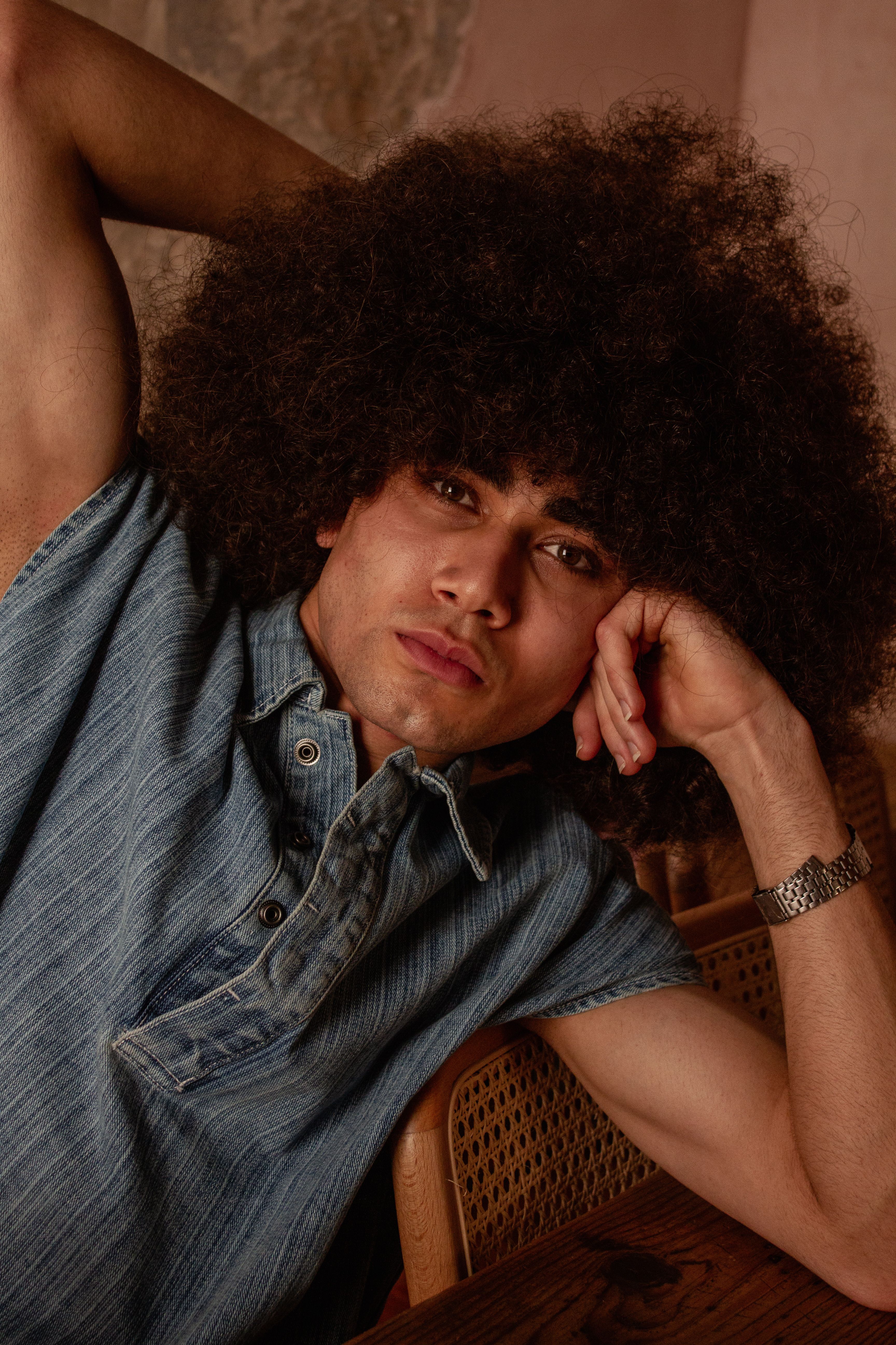 Portrait of a young man with afro hair in denim shirt, exuding a relaxed and stylish vibe.
