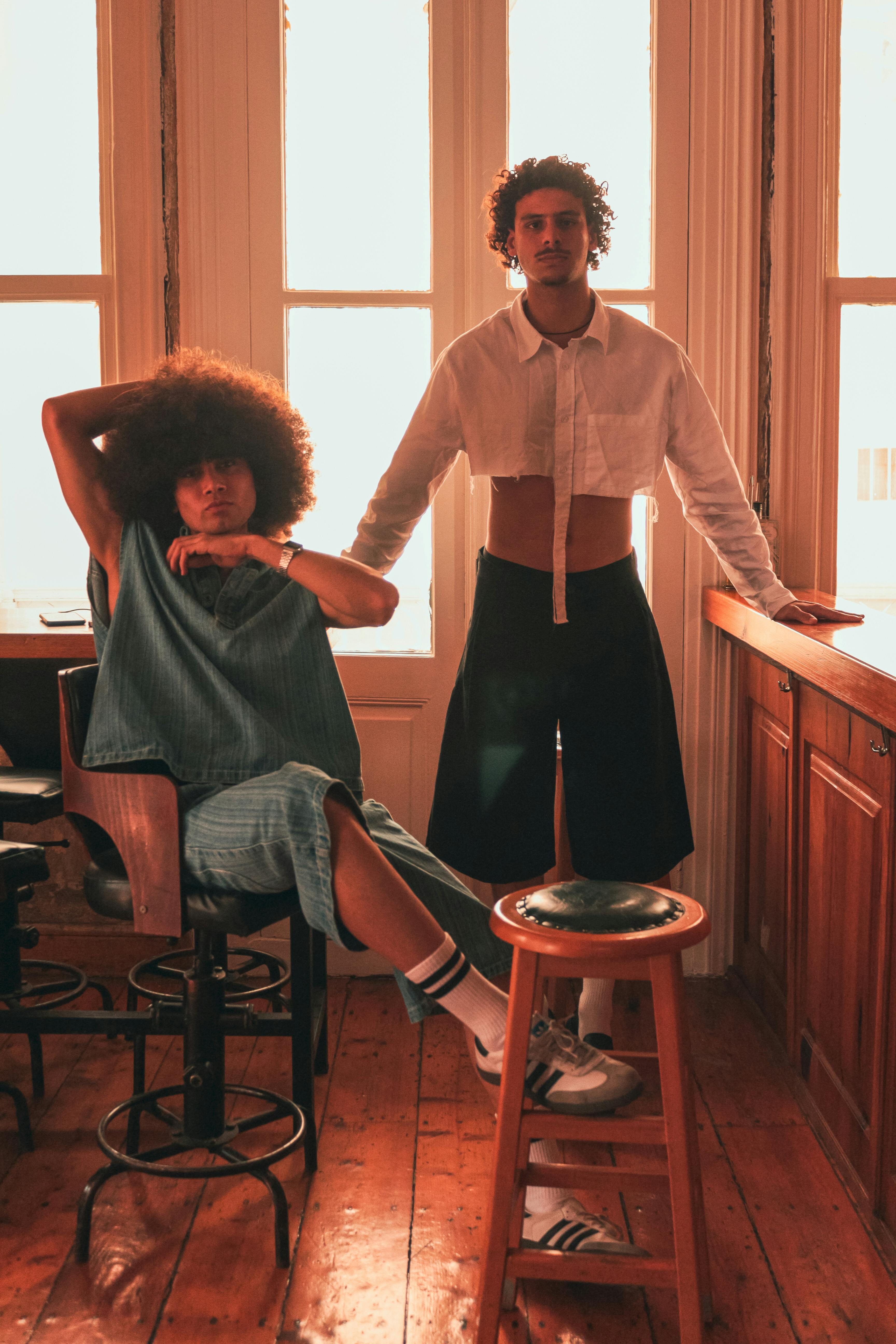 Free Stylish couple posing indoors with warm sunlight through windows, modern fashion. Stock Photo