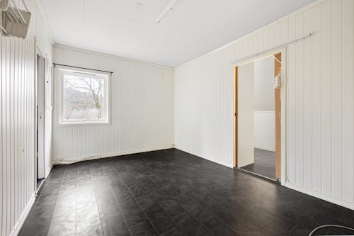 An empty room with black flooring and white walls