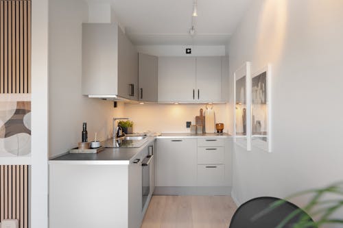 A small kitchen with white cabinets and a white table