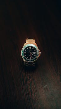 A sophisticated wristwatch resting on a dark wooden table with a black background in a studio setting.