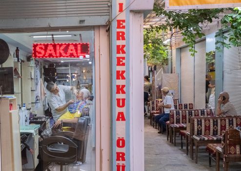 Authentic barber shop scene in İzmir with men getting haircuts and shaves.