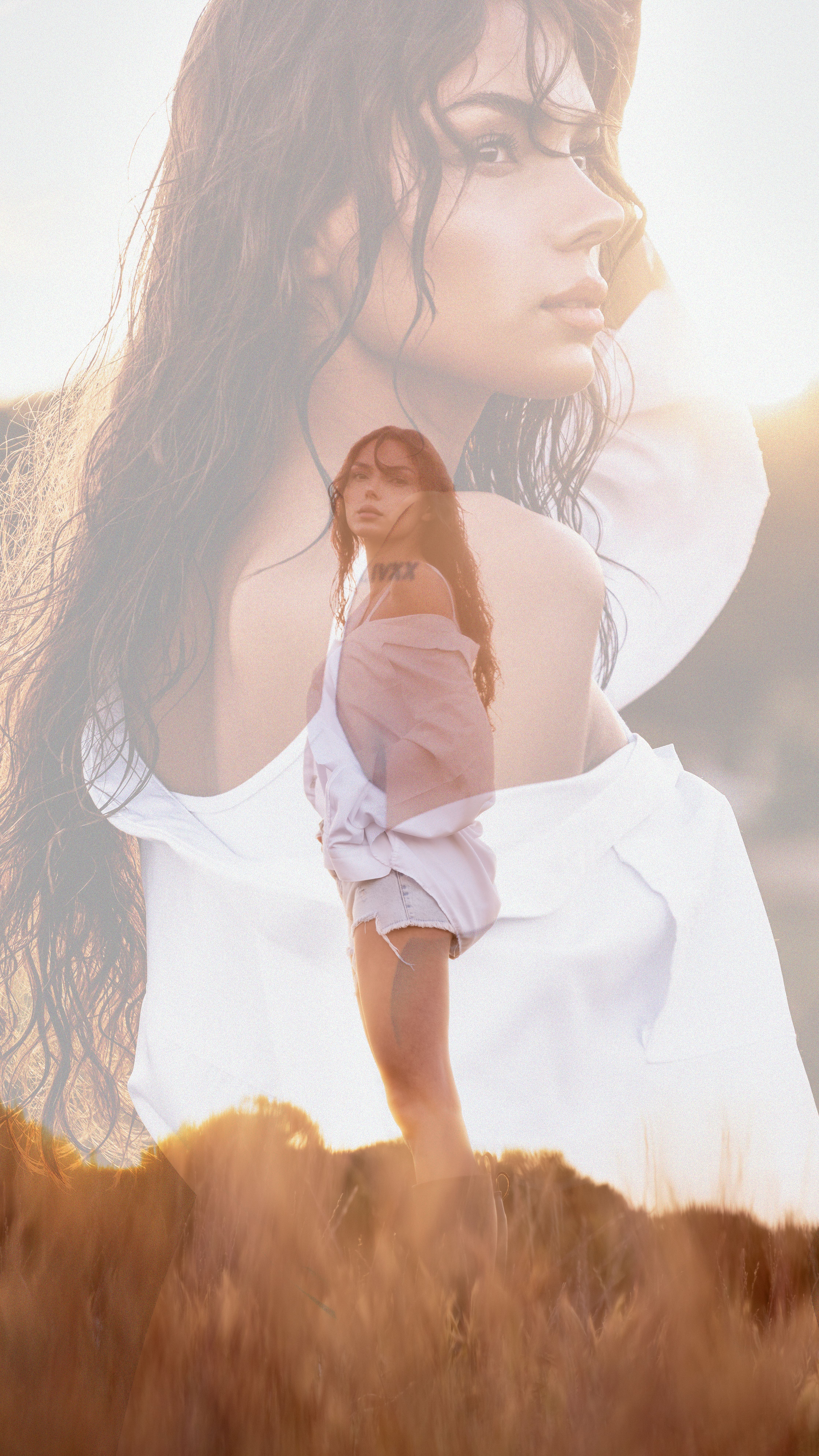 Artistic double exposure of a woman in a meadow with a dreamy sunlit atmosphere.
