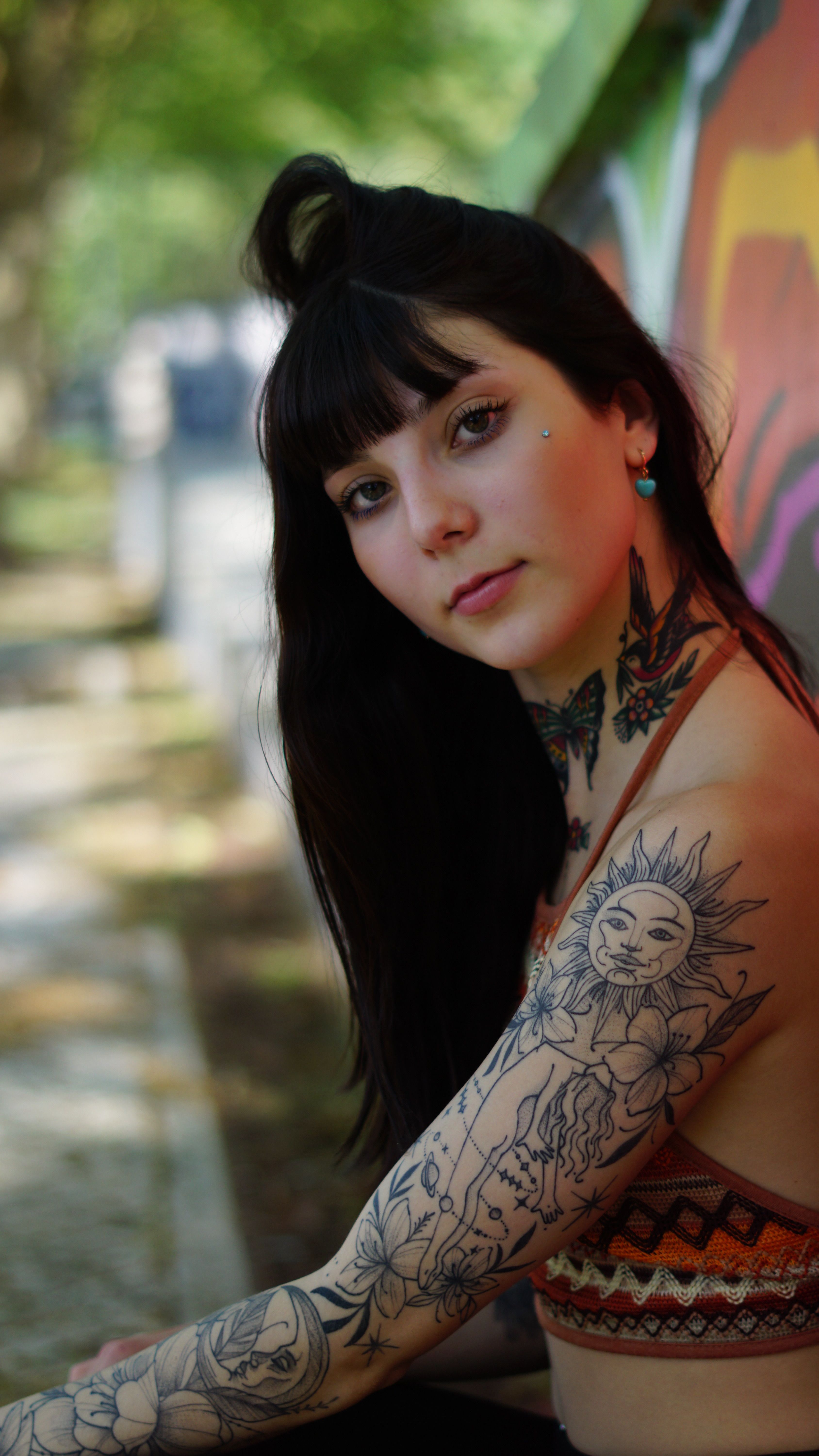 Portrait of a young woman with tattoos, outdoors, long brunette hair.