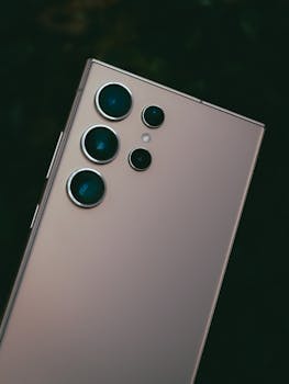 Detailed view of a smartphone's multiple lens camera setup in low light.