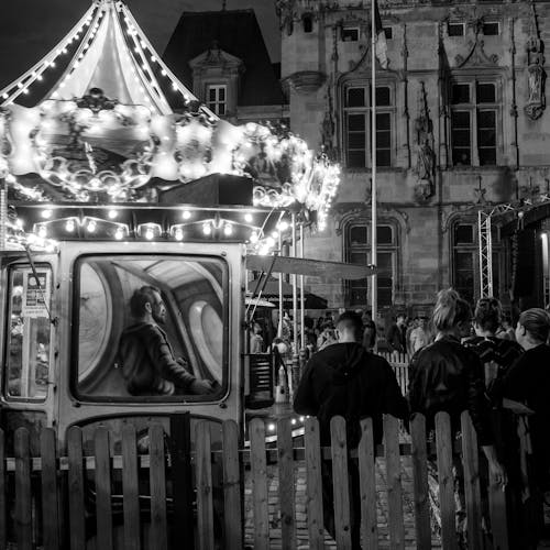 A black and white photo of people standing around a carousel