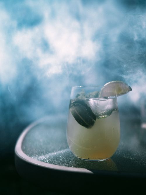 Free Inviting cocktail with lime and ice, set against a smoky backdrop for a cool refreshment vibe. Stock Photo