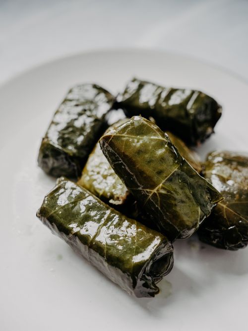 Free A mouth-watering close-up of freshly cooked stuffed grape leaves arranged on a white plate. Stock Photo