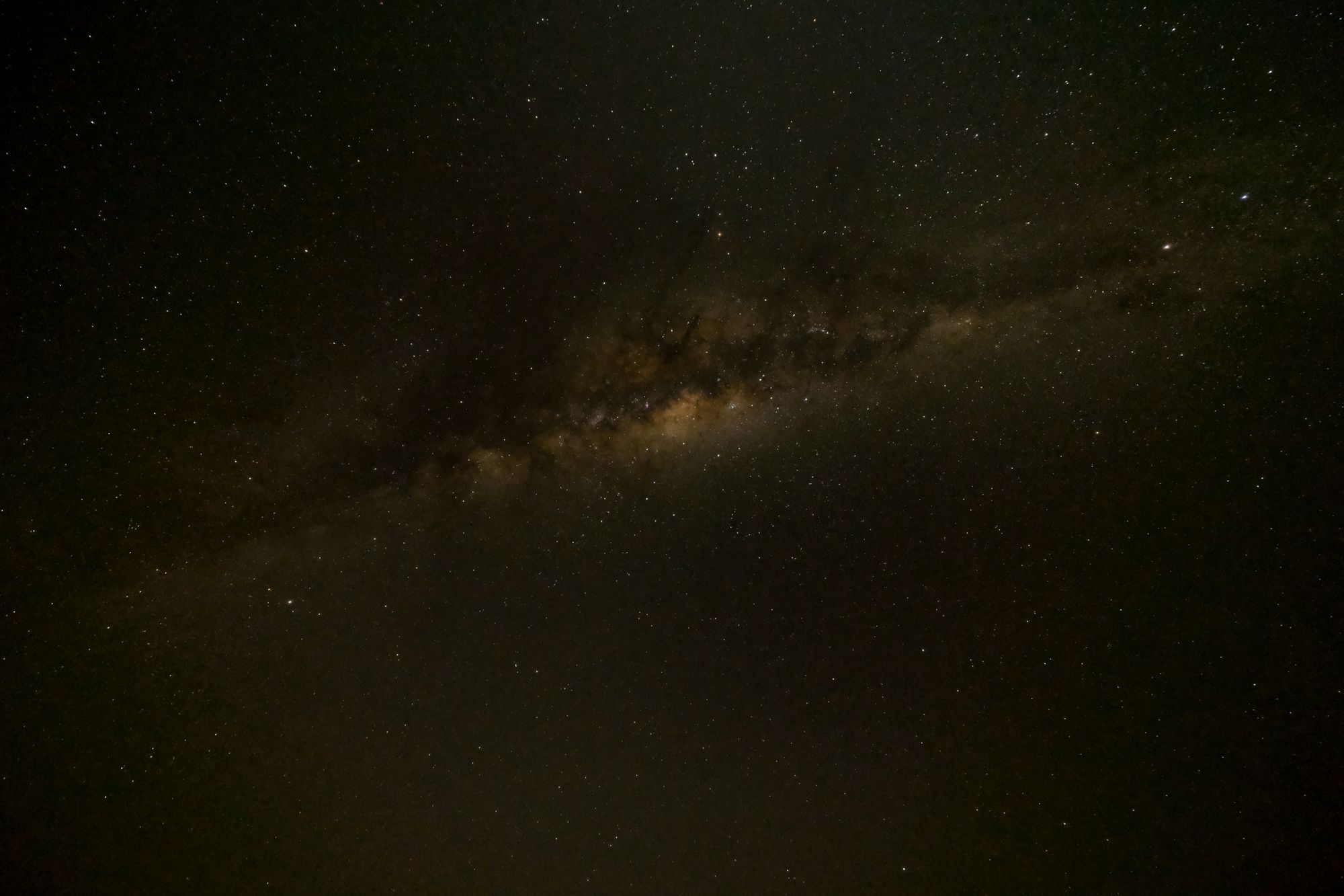 Cielo nocturno con la banda de la Vía Láctea sobre un horizonte oscuro y despejado