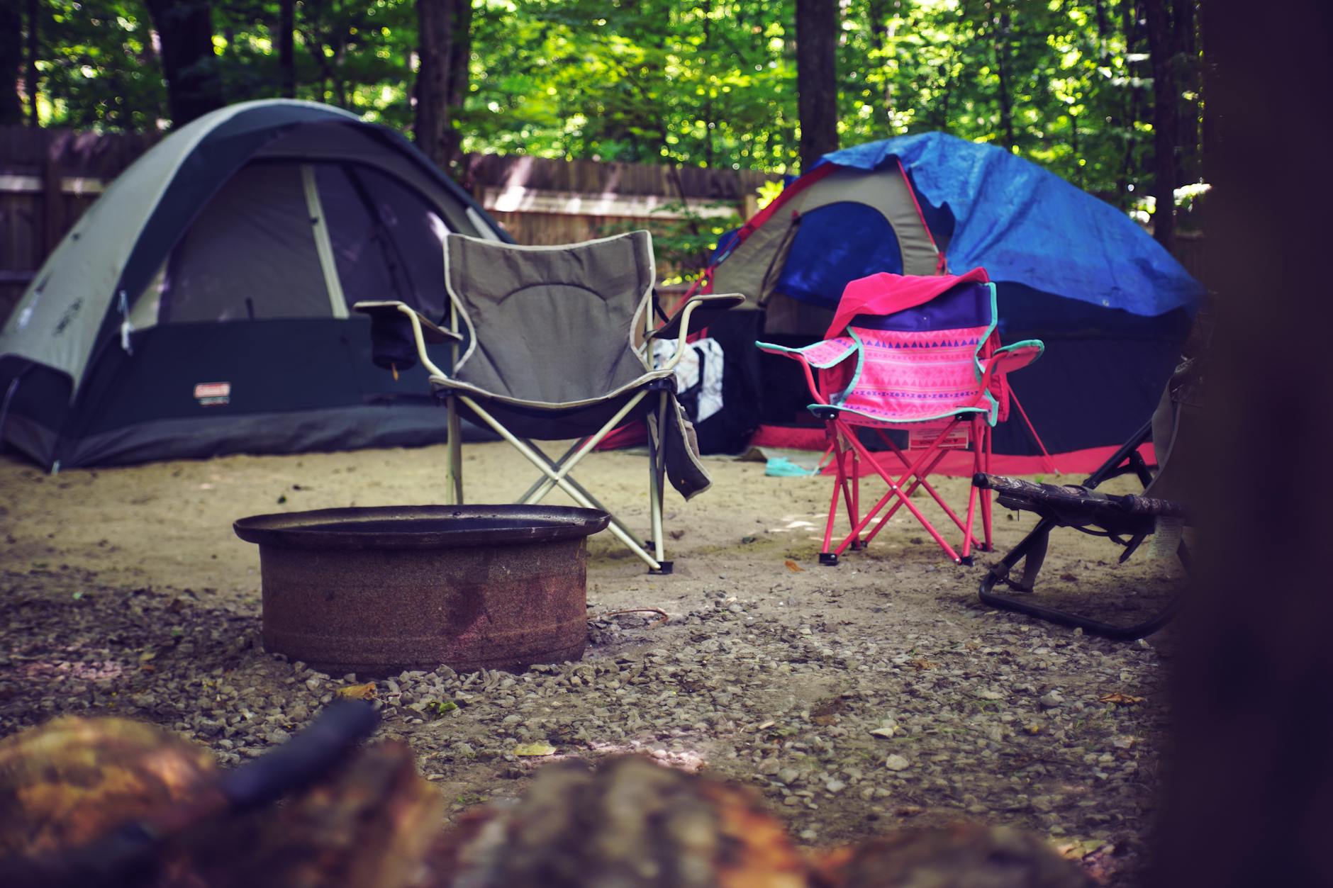 Two chairs and two tents in a cosy camping scene.