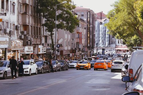Free Vibrant city street scene featuring taxis, parked cars, and pedestrians on a sunny day. Stock Photo