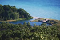 探索森林覆盖的湖岸与清澈蔚蓝海水交汇的惊人鸟瞰图，这是完美的夏季景致