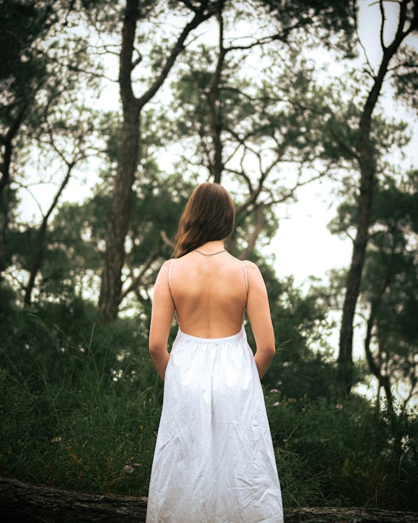 A woman in a white dress standing in the woods