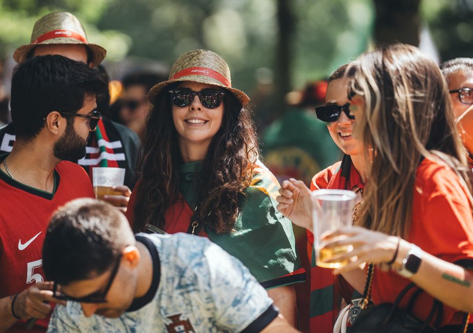 Group of smiling soccer fans enjoying drinks and camaraderie at an outdoor event.
