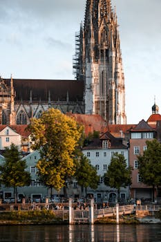 Beautiful view of Regensburg Cathedral with colorful houses along the Danube river at sunset.