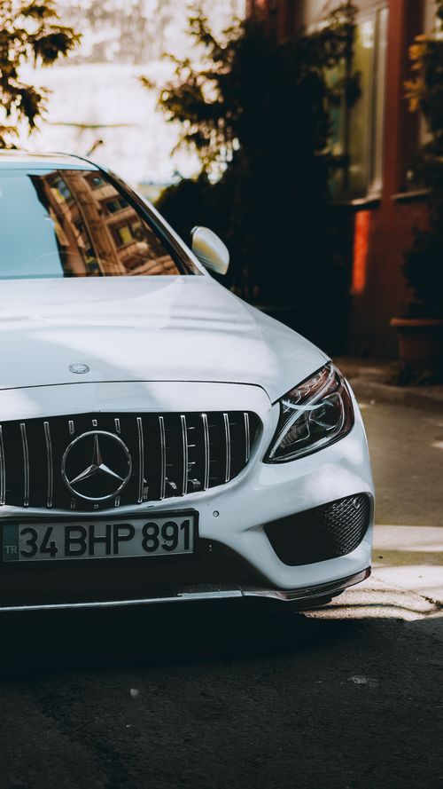 Free Close-up of a white luxury car parked on city street capturing elegant design. Stock Photo