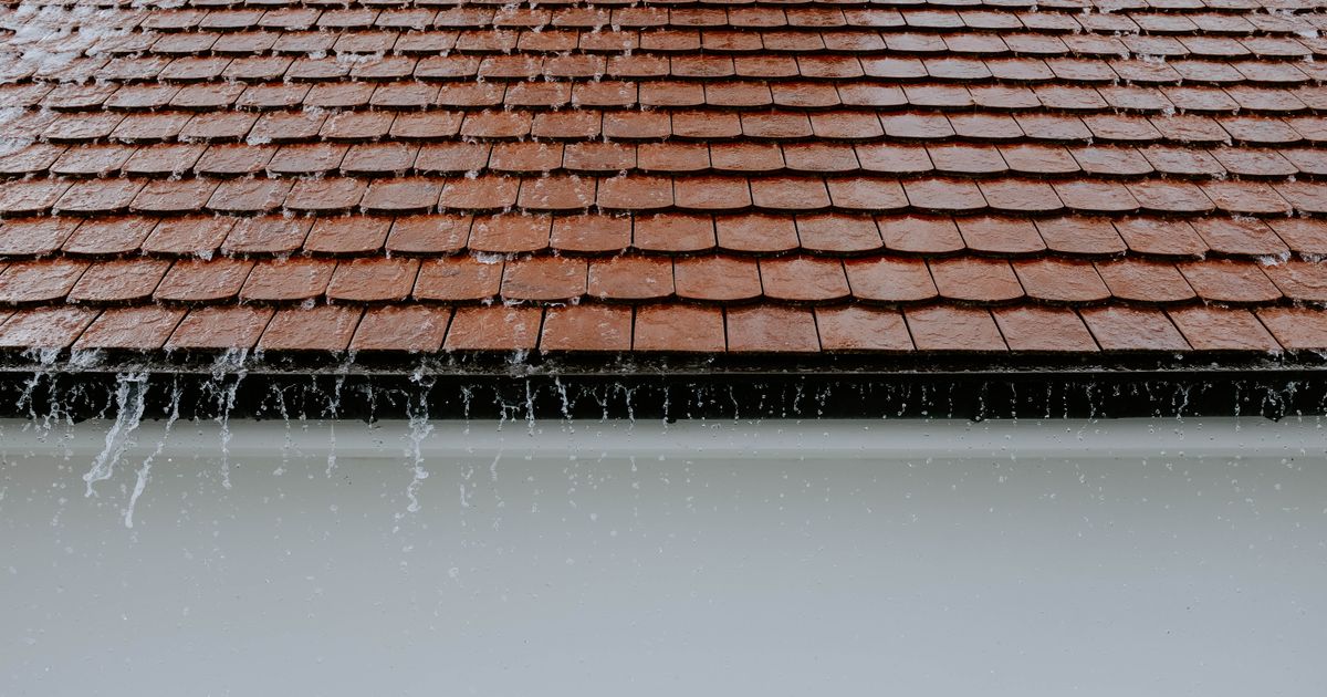 Rainwater running off brown barrel-tile roofing, the kind of roof system that drives windstorm pricing on a South Florida homeowners policy