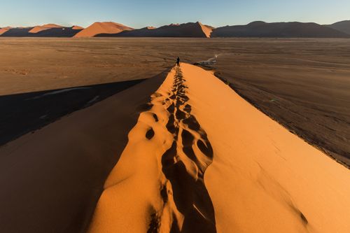 Free Explore the breathtaking beauty of the Namib Desert with its sunlit dunes and expansive landscape captured at sunset. Stock Photo