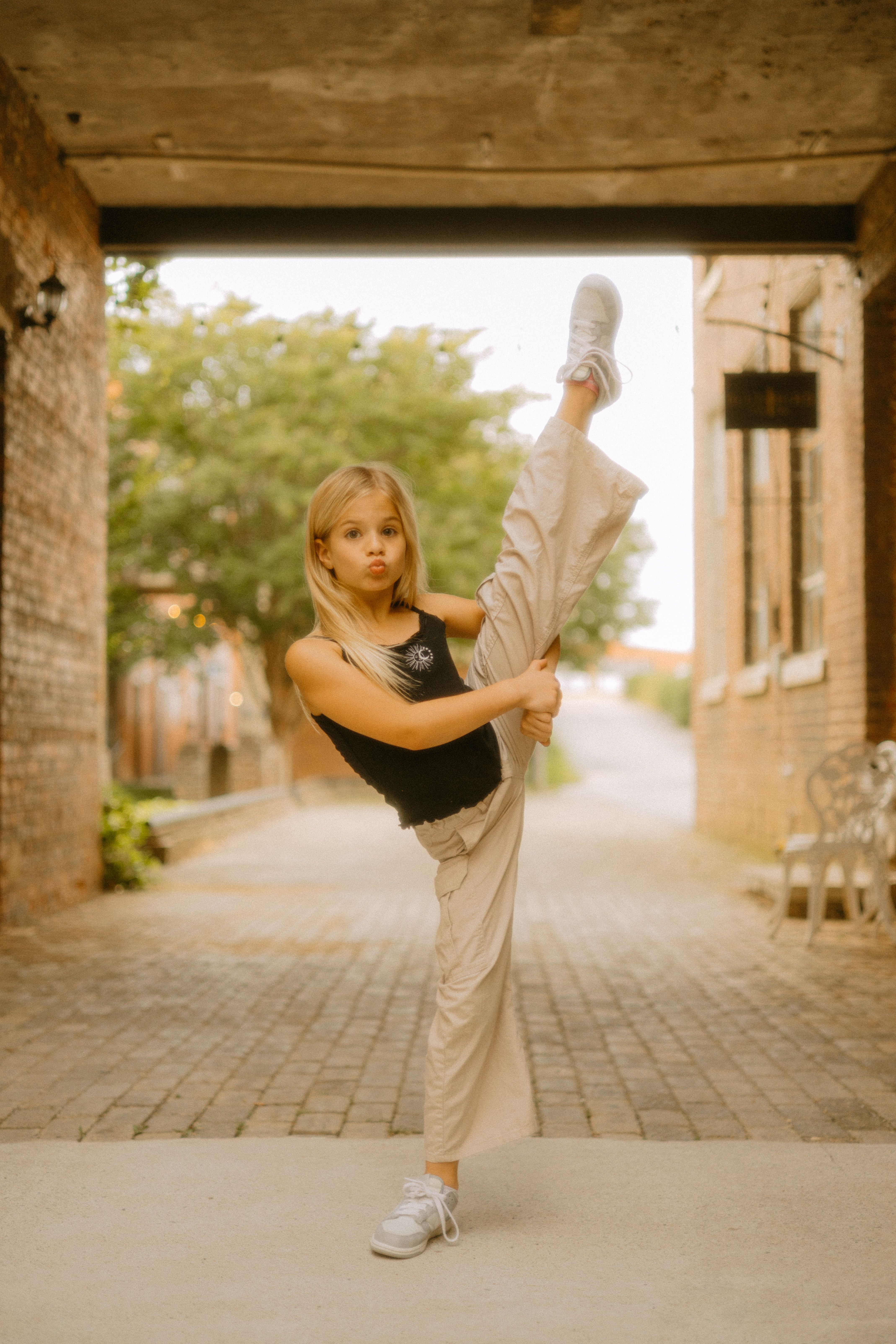 Blonde girl in a black top performs a standing split on a cobblestone street in TN, USA.