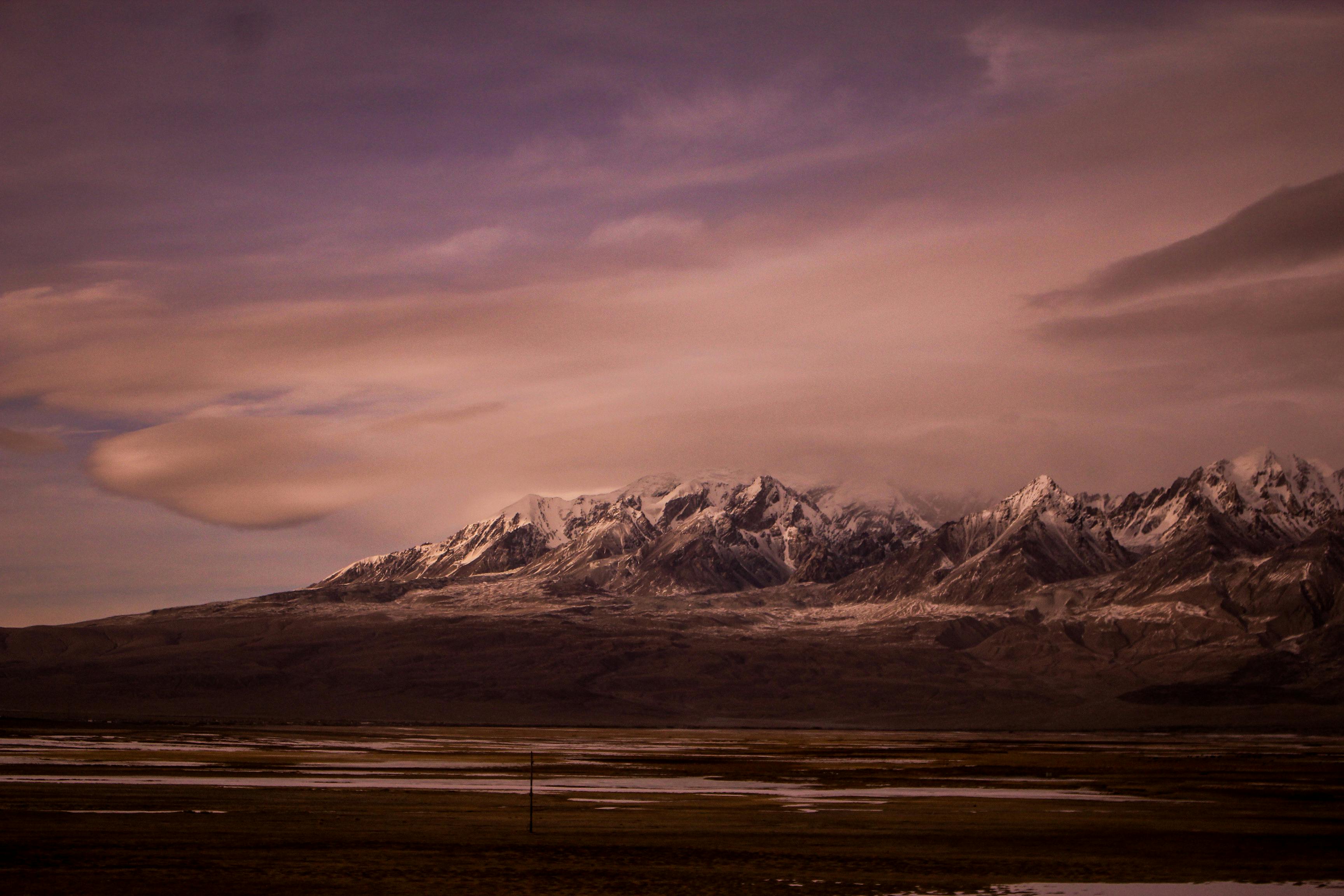 在壮观的夜空下，雄伟的雪山覆盖着大地，营造出宁静的景观