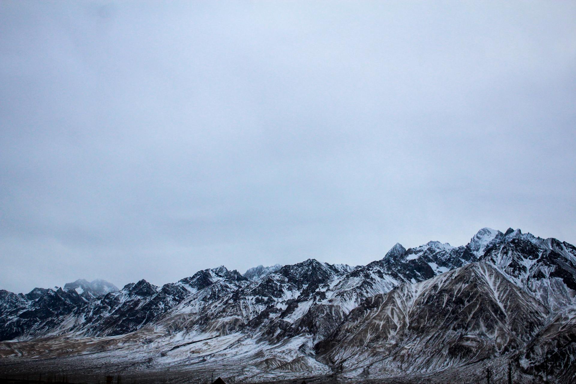 Breathtaking view of snow-covered mountains in Kashgar, Xinjiang, China under a cloudy sky.