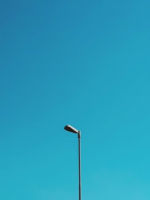 A single street lamp set against a vast blue sky, capturing minimalist aesthetics.