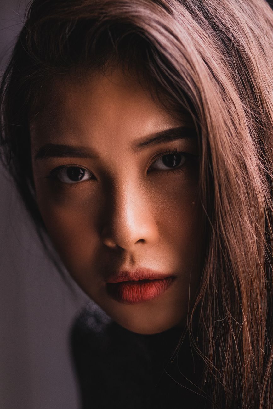 Close-up studio portrait of a young woman with an intense gaze and natural hairstyle.