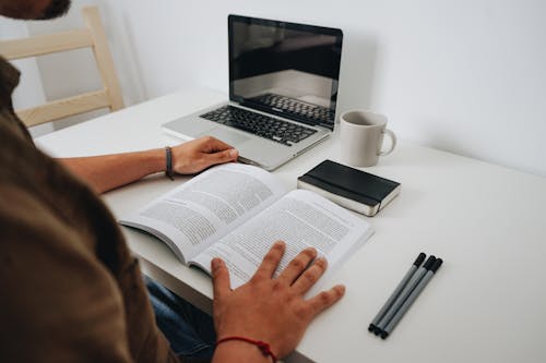 Photo of Man Sitting While Reading a Book