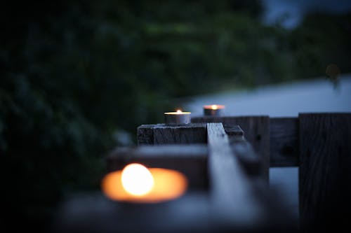 Selective Focus Photo of Three Tealight on Brown Planks