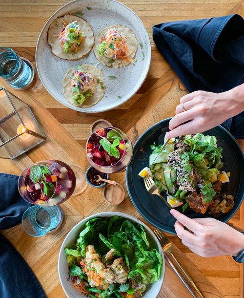 Free Top view of a vibrant vegetarian meal with tacos, salads, and refreshing beverages on a wooden table. Stock Photo