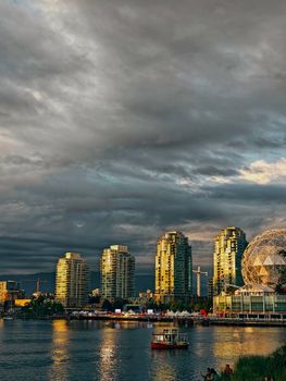 Urban skyline under dramatic stormy skies, reflecting in a calm river at dusk for a moody cityscape view.