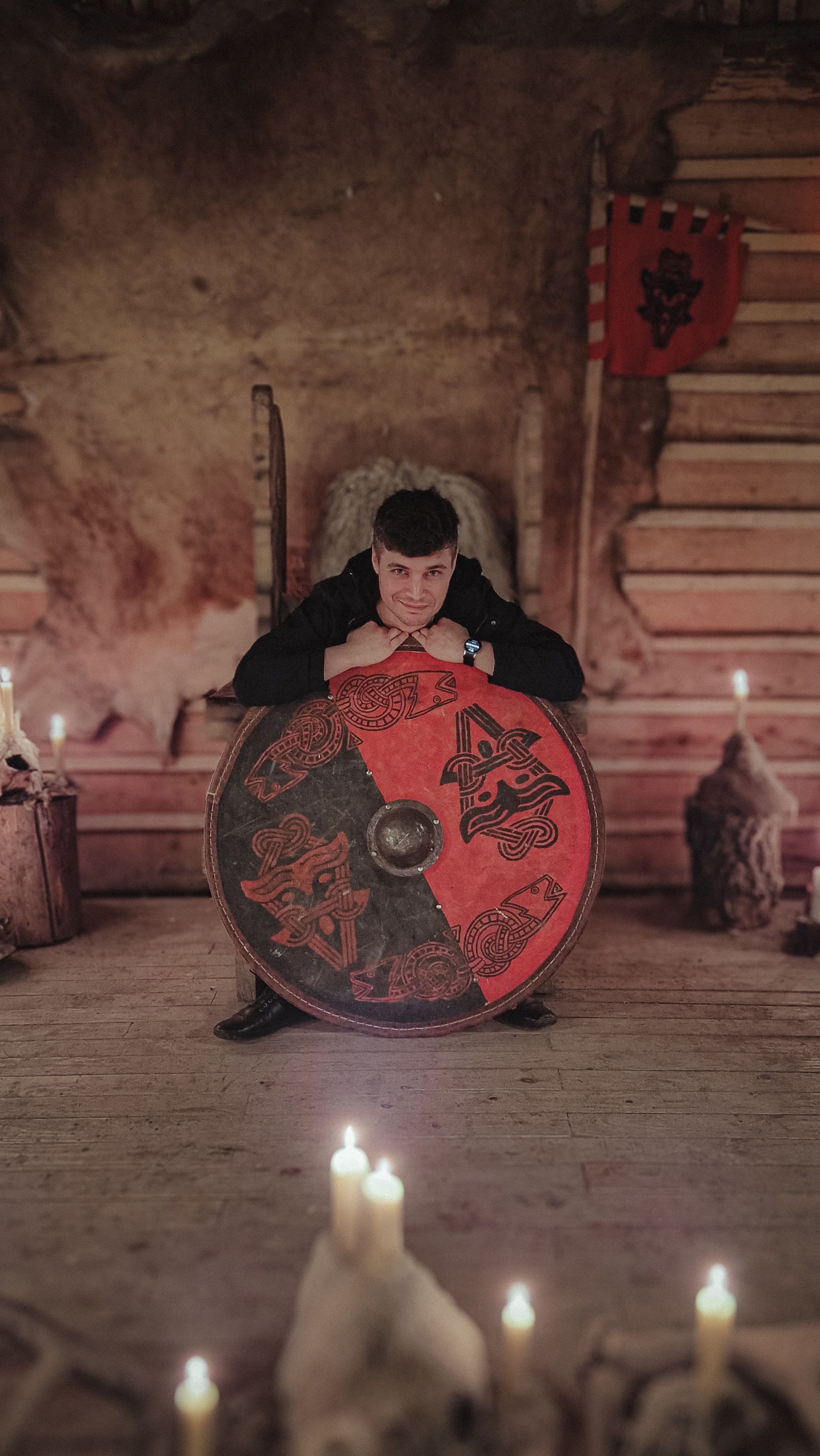 Portrait of a man with a medieval shield surrounded by candles, creating a mysterious ambiance.
