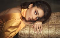 一位身穿优雅金色丝绸服装的女子，优雅地躺在纹理表面上