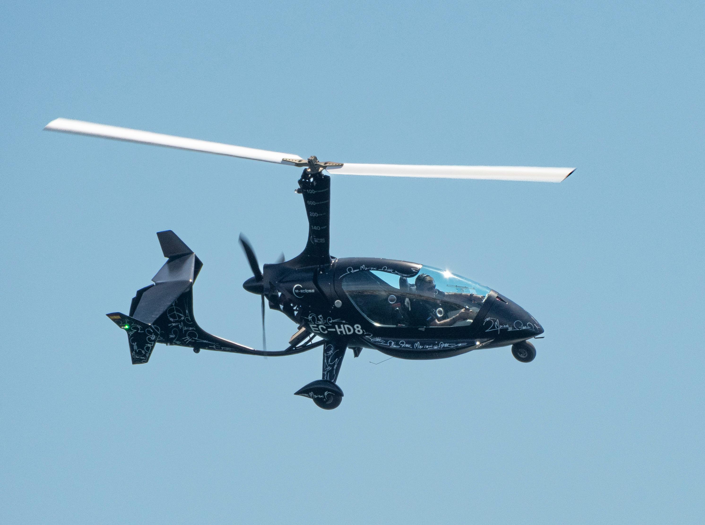 Free Autogyro flying against a clear sky in San Javier, Spain, showcasing modern aviation technology. Stock Photo