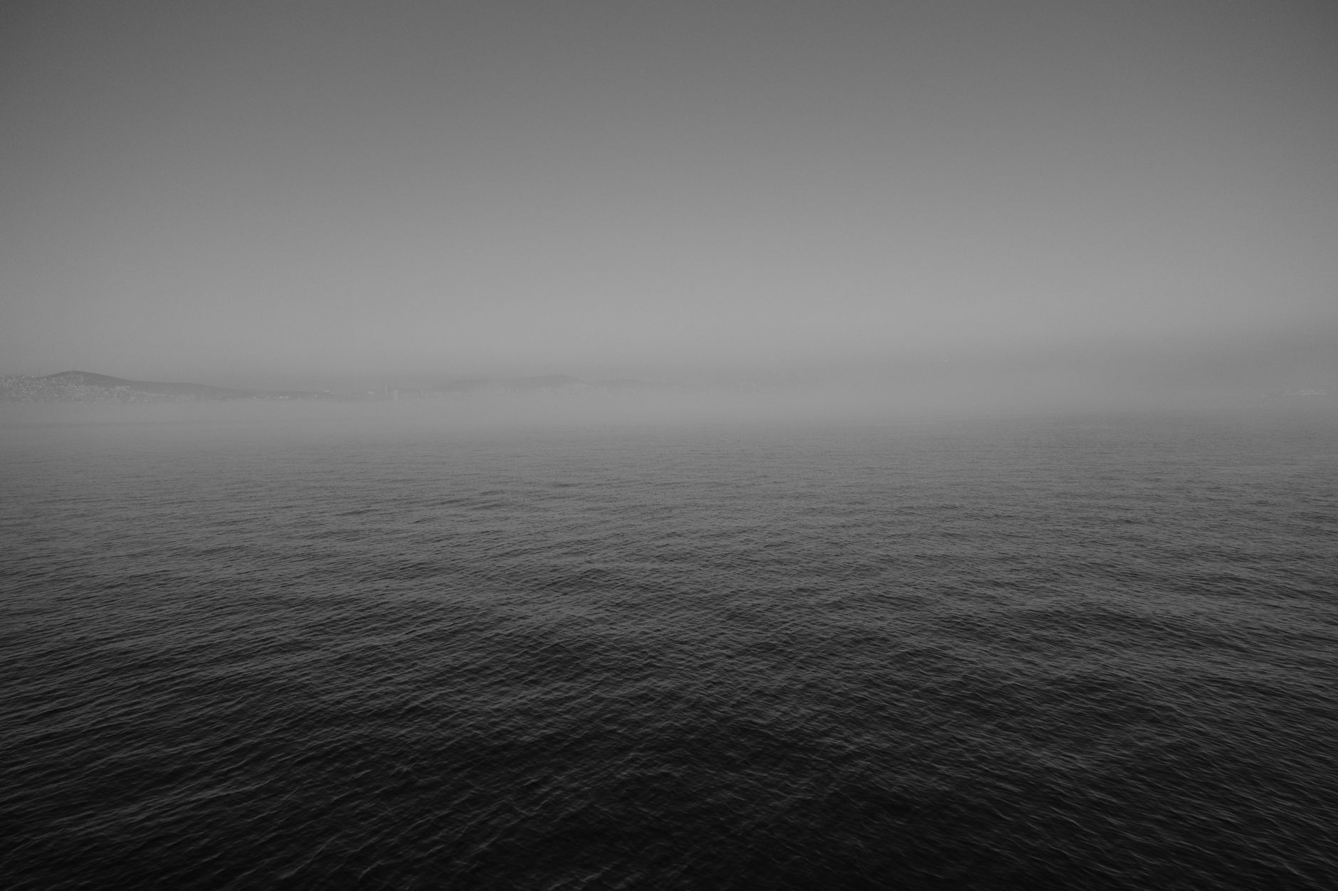 Thick ocean fog over a calm grey sea, conveying the isolation of the North Atlantic in winter.