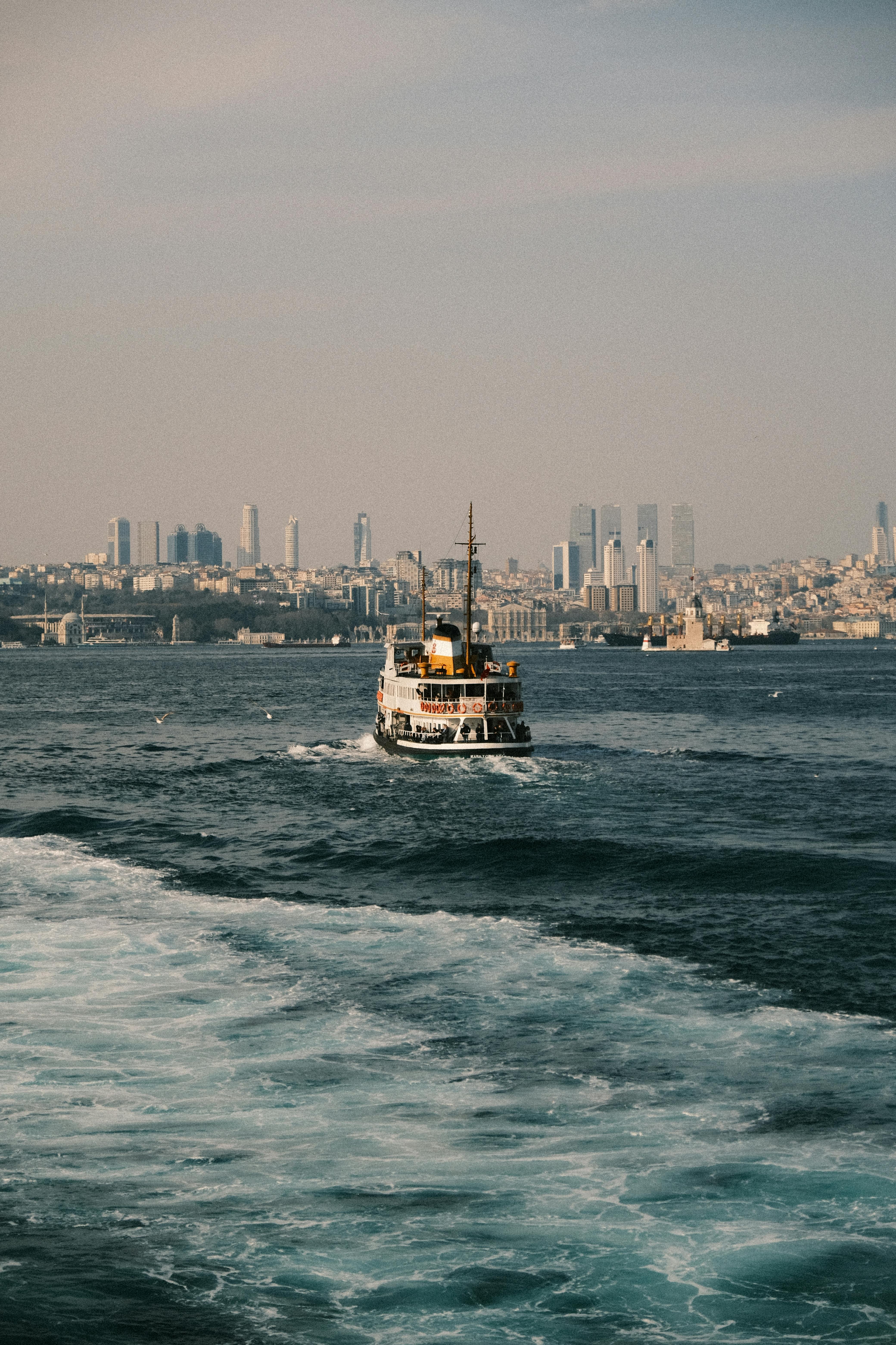 A ferry sails across the Bosphorus in front of Istanbul's iconic skyline, capturing urban and maritime beauty.