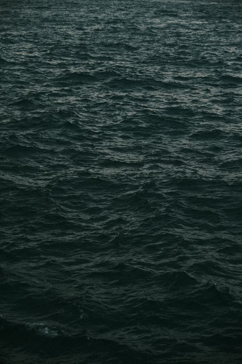 Free A serene view of dark ocean waves creating a textured pattern under overcast skies. Stock Photo