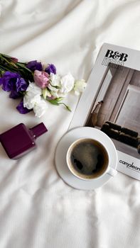A stylish flat lay featuring coffee, a magazine, flowers, and a perfume bottle.