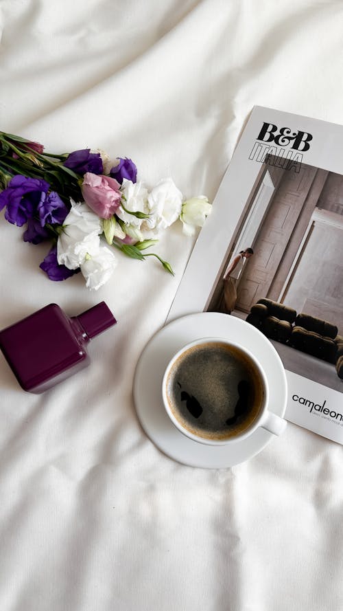 Free A coffee cup and a magazine on a bed Stock Photo