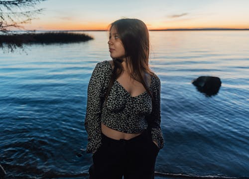 A woman standing by the water at sunset