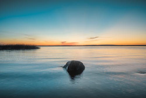 A rock in the water at sunset