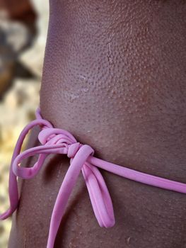 Detailed close-up of wet skin with a pink bikini string, showing texture.
