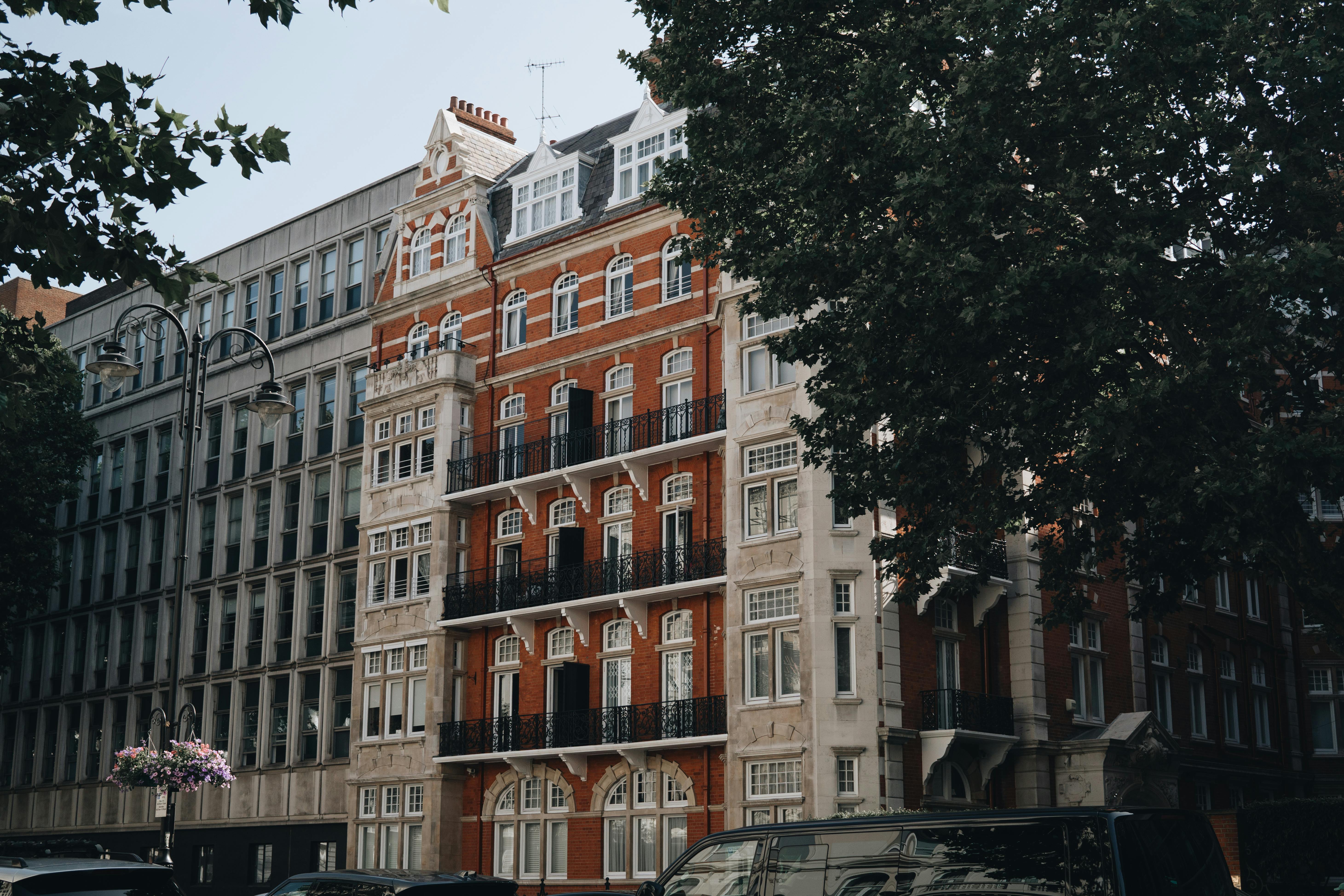 Elegant red brick building in an urban setting, surrounded by trees and adjacent structures. Daytime cityscape.
