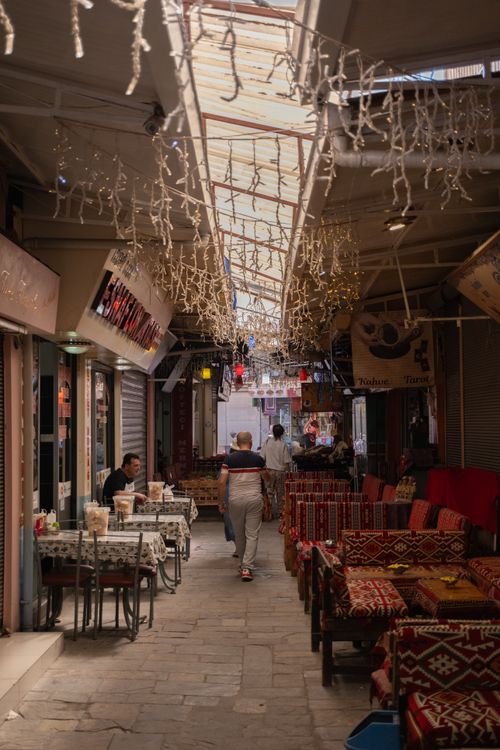 Free Explore a bustling cafe alley in İzmir's vibrant bazaar featuring colorful seating and lively atmosphere. Stock Photo