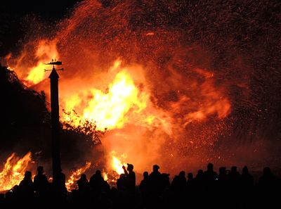 People watching a large bonfire at night, photo by Pixabay on Pexels